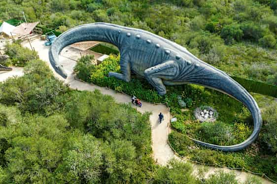 En stor dinosaurstatue omgivet af grønt set oppefra. (AI-genereret tekst)