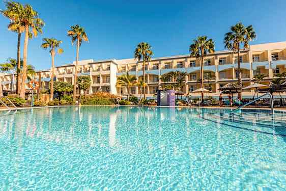 En udendørs pool omgivet af palmer og et hotel i baggrunden. (AI-genereret tekst)