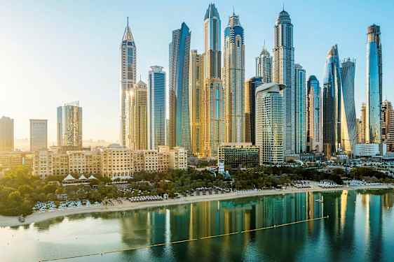 Skyline med høje bygninger og en strand ved vandet i forgrunden. (AI-genereret tekst)