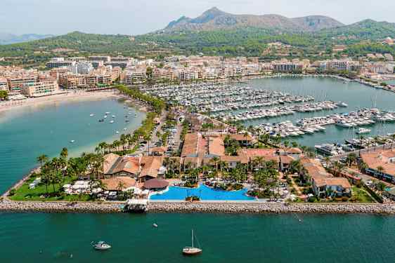 Luftfoto af et havneområde med både og omkringliggende bygninger. (AI-genereret tekst)