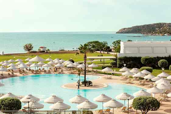 En pool med liggestole og parasoller, med udsigt til havet og frodige omgivelser. (AI-genereret tekst)