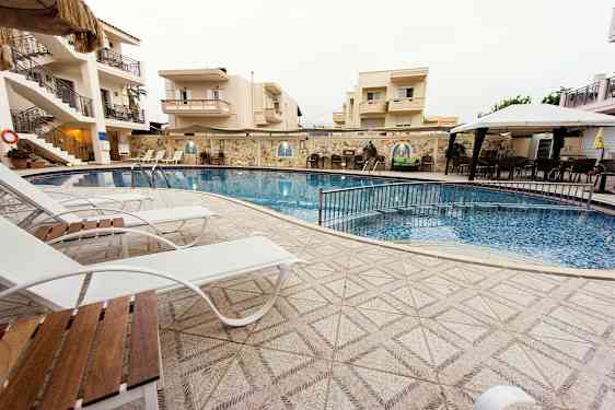 Udendørs pool ved hotel, omgivet af liggestole og bygninger. (AI-genereret tekst)