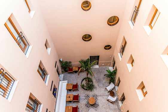 En gårdhave set ovenfra med borde, stole og træer. (AI-genereret tekst)