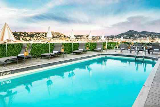 Udendørs swimmingpool med liggestole og parasoller. (AI-genereret tekst)