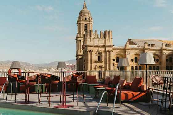 En tagterrasse med pool og loungemøbler, med en historisk bygning i baggrunden. (AI-genereret tekst)