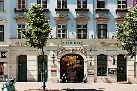 En bygning med vinduer, bueindgang og blomsterkasser ved vinduerne. (AI-genereret tekst)