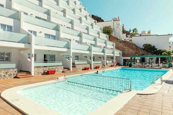 Billede af hotelkompleks med pool og siddeområde. (AI-genereret tekst)