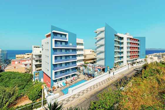 Billede af to moderne hotelbygninger med blå facader, en swimmingpool og liggestole i forgrunden. (AI-genereret tekst)