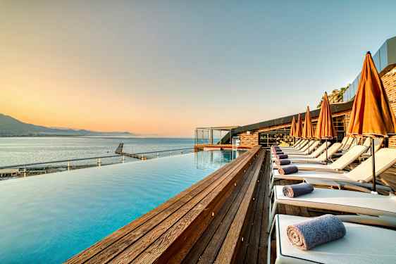 Strandområde med swimmingpool, liggestole og orange parasoller. (AI-genereret tekst)