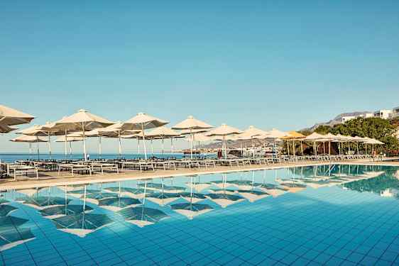 Solsenge og parasoller ved en pool med udsigt over havet. (AI-genereret tekst)