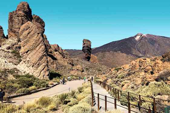 En klippeformation med gangsti og bjerge i baggrunden. (AI-genereret tekst)