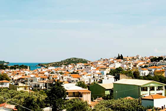 Panoramisk udsigt over en by med hvide bygninger og røde tage nær kysten. (AI-genereret tekst)