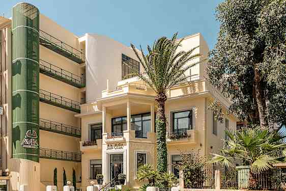 Billede af en hotelbygning omgivet af palmer. (AI-genereret tekst)