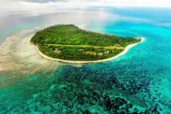 Luftudsigt over en tropisk ø omgivet af blåt hav og koralrev. (AI-genereret tekst)