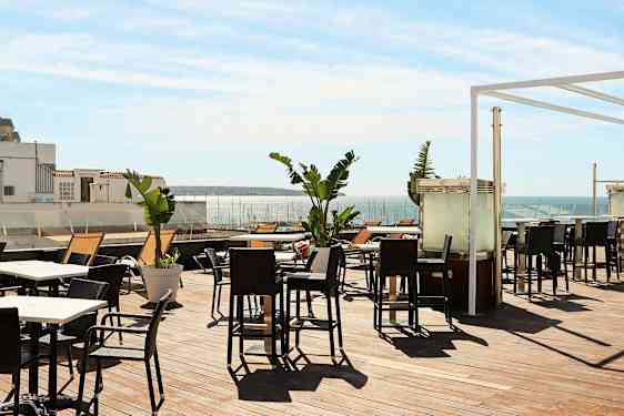 Terrasse med udendørsmøbler og udsigt over havet. (AI-genereret tekst)