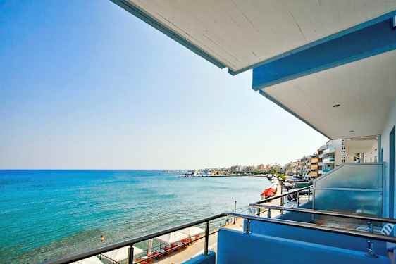 Udsigt fra en balkon over havet og en strandpromenade. (AI-genereret tekst)