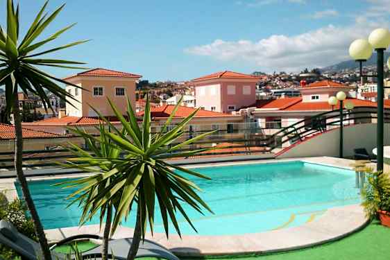 En pool omgivet af grønne områder og en baggrund med huse med røde tegltage. (AI-genereret tekst)