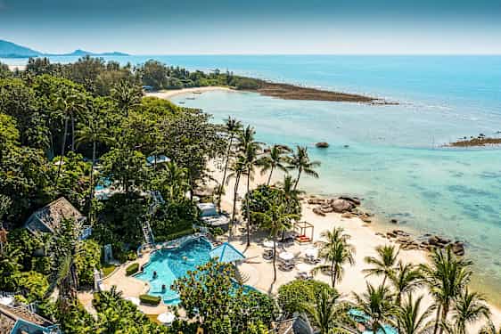 Et tropisk landskab med en strand omgivet af palmer og klart blåt vand. Der er en pool og grønne områder i forgrunden. (AI-genereret tekst)