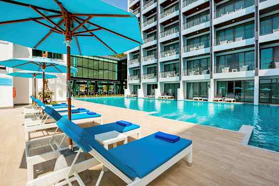 En swimmingpool på et hotel med liggestole og parasoller i forgrunden. (AI-genereret tekst)