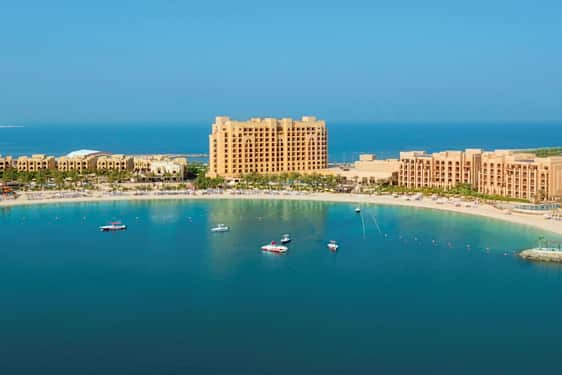 Hotelkompleks ved en sandstrand og havbugt. (AI-genereret tekst)