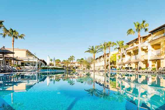 Hotelbygninger og swimmingpool med liggestole ved poolkanten. (AI-genereret tekst)