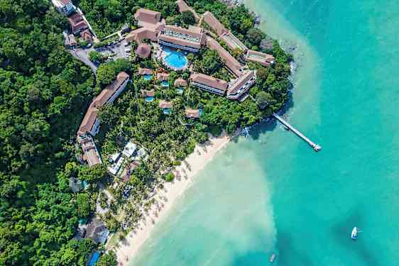 Luftfoto af et resort ved en sandstrand og turkis vand. (AI-genereret tekst)