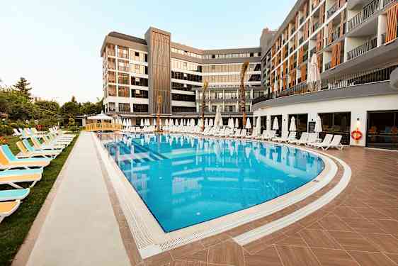 Udendørs swimmingpool omgivet af liggestole og parasoller ved et moderne hotel. (AI-genereret tekst)