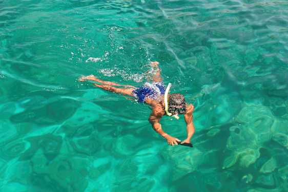 En person svømmer i klart vand med snorkeludstyr. (AI-genereret tekst)