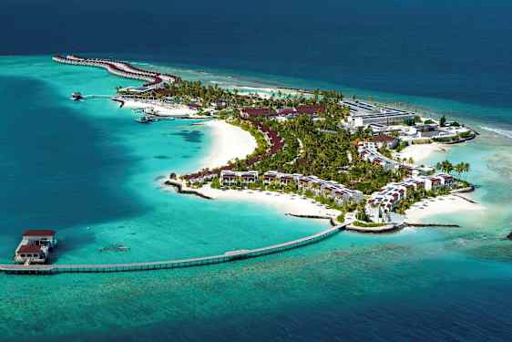 En ø med resortbygninger omgivet af turkis vand. (AI-genereret tekst)