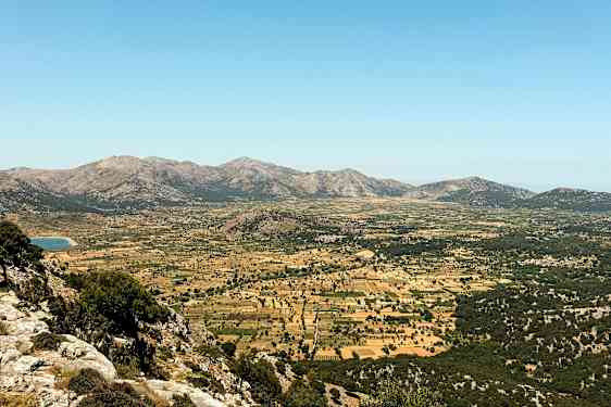 En bred dal omgivet af bjerge med græsgange og marker. (AI-genereret tekst)