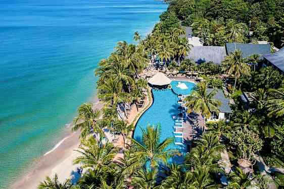 Luftfoto af en strandresort med pool, liggestole og palmer nær havet. (AI-genereret tekst)