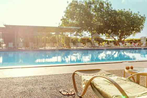 En liggestol og et bord ved kanten af en swimmingpool. (AI-genereret tekst)