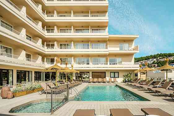 Billede af et hotel med altaner og en udendørs pool omgivet af liggestole. (AI-genereret tekst)