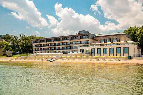 Fleretages hotel ved stranden med gule parasoller og klar blå himmel. (AI-genereret tekst)