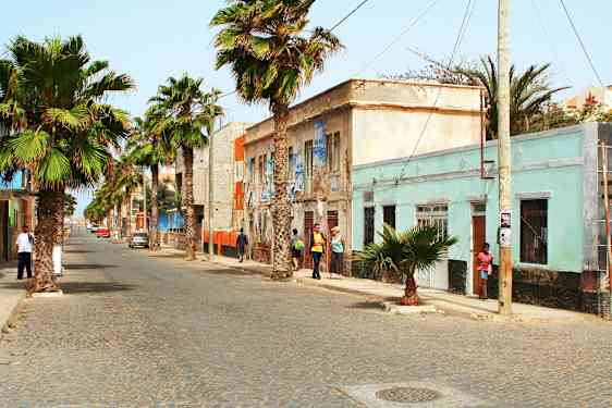 Gade med palmer og farverige bygninger. (AI-genereret tekst)