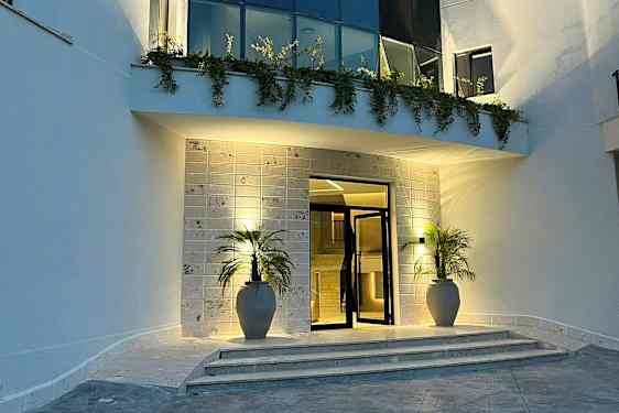 Indgang med to potter, trapper og belysning om aftenen. (AI-genereret tekst)