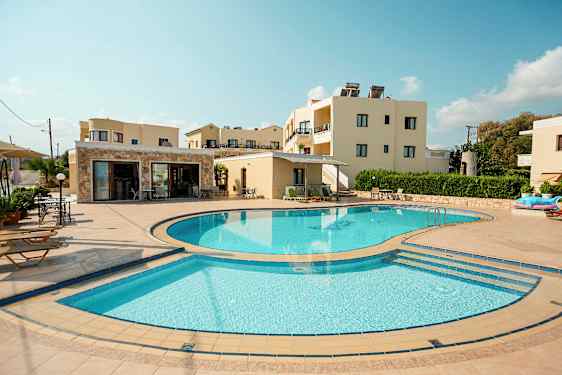 Et billede, der viser en udendørspool omgivet af liggestole og bygninger i baggrunden. (AI-genereret tekst)