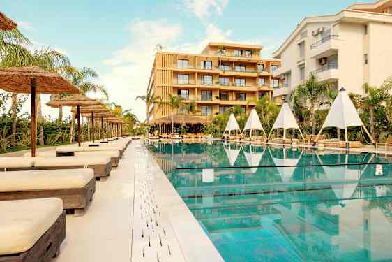 Udendørs swimmingpool med liggestole og parasoller ved et hotel. (AI-genereret tekst)