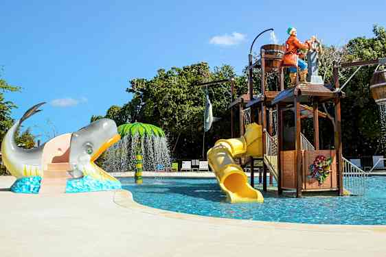 En børnepool med vandrutsjebaner, pirattema og figurer som en hval og en palme. (AI-genereret tekst)