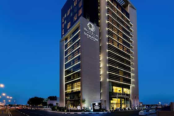 Højt hotel med en moderne facade mod en mørkeblå aftenshimmel. (AI-genereret tekst)