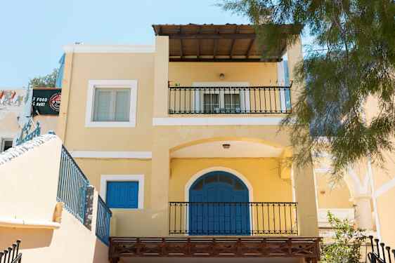 Gul bygning med blå døre og balkoner. (AI-genereret tekst)