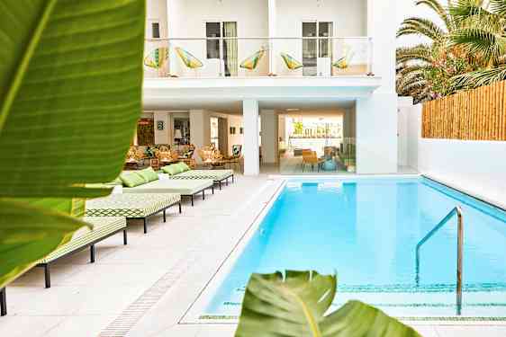 Udendørs pool ved hotel med liggestole og frodige omgivelser. (AI-genereret tekst)