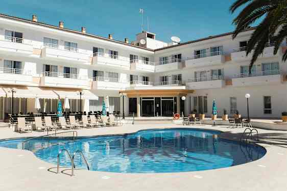 En pool foran et hotelanlæg med liggestole og parasoller. (AI-genereret tekst)