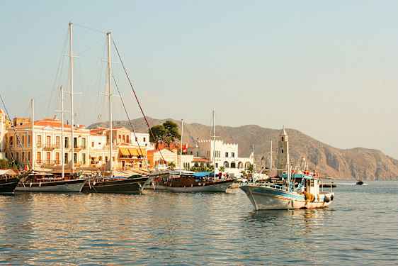 En havn med både og bygninger, bjerge ses i baggrunden. (AI-genereret tekst)