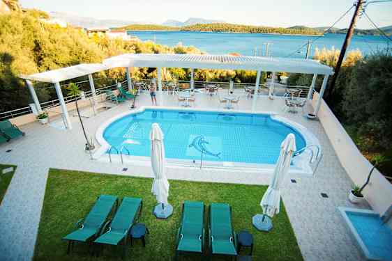 Billede af et udendørs poolområde med solsenge og en frodig udsigt i baggrunden. (AI-genereret tekst)