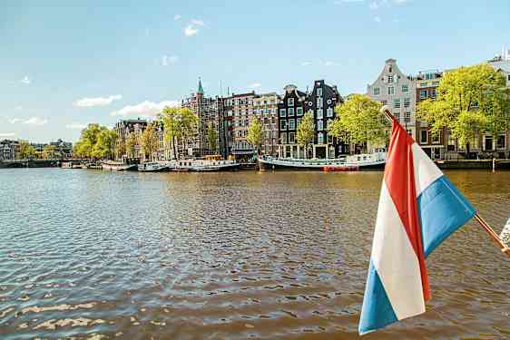 Et billede af en kanal med huse på række, et nederlandsk flag synligt i forgrunden. (AI-genereret tekst)