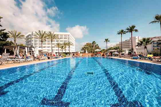 Udendørs pool ved hotel med liggestole og palmer. (AI-genereret tekst)