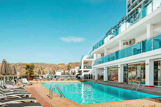 Poolområde ved hotel med liggestole og parasoller. (AI-genereret tekst)