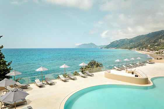 Udsigt over en pool og havet med liggestole og parasoller på en terrasse. (AI-genereret tekst)