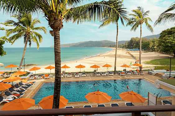 En strand med en pool i forgrunden, omgivet af liggestole og parasoller. (AI-genereret tekst)